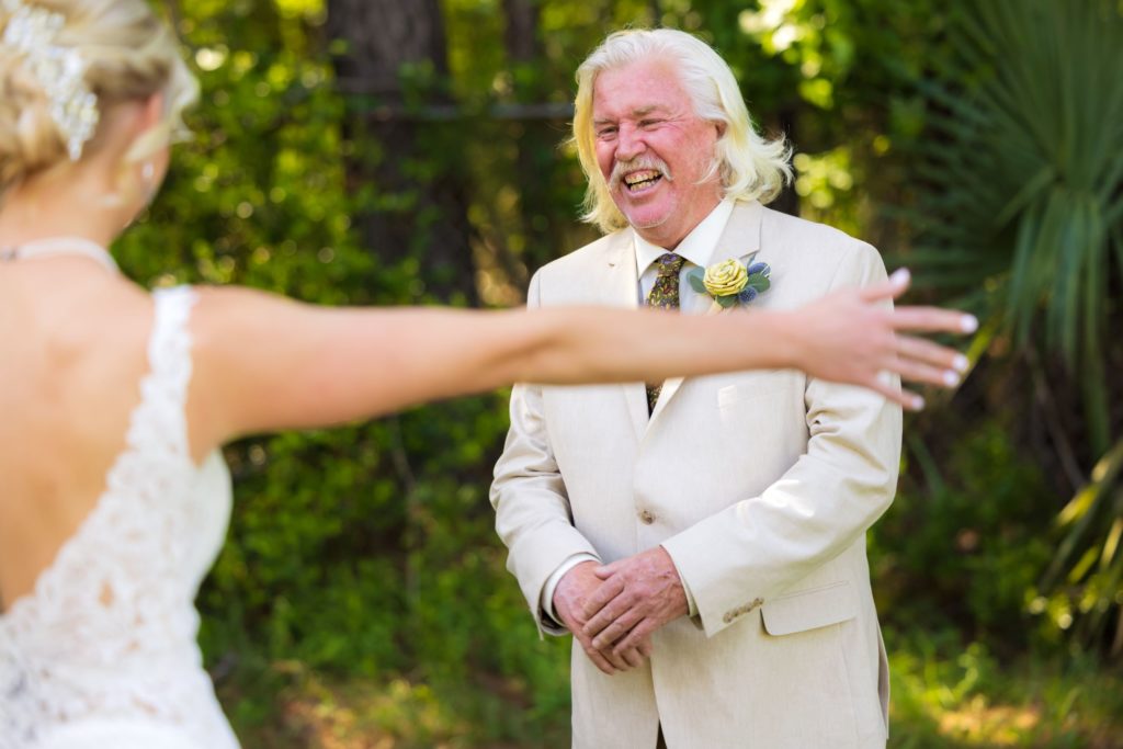 Bride's father smiles in delight during his first look at her before her Wando River Grill wedding ceremony.