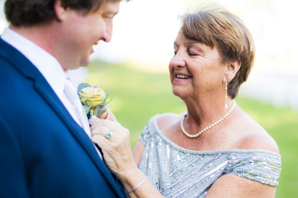Groom's mother pins flower to jacket before his Wando River Grill wedding.
